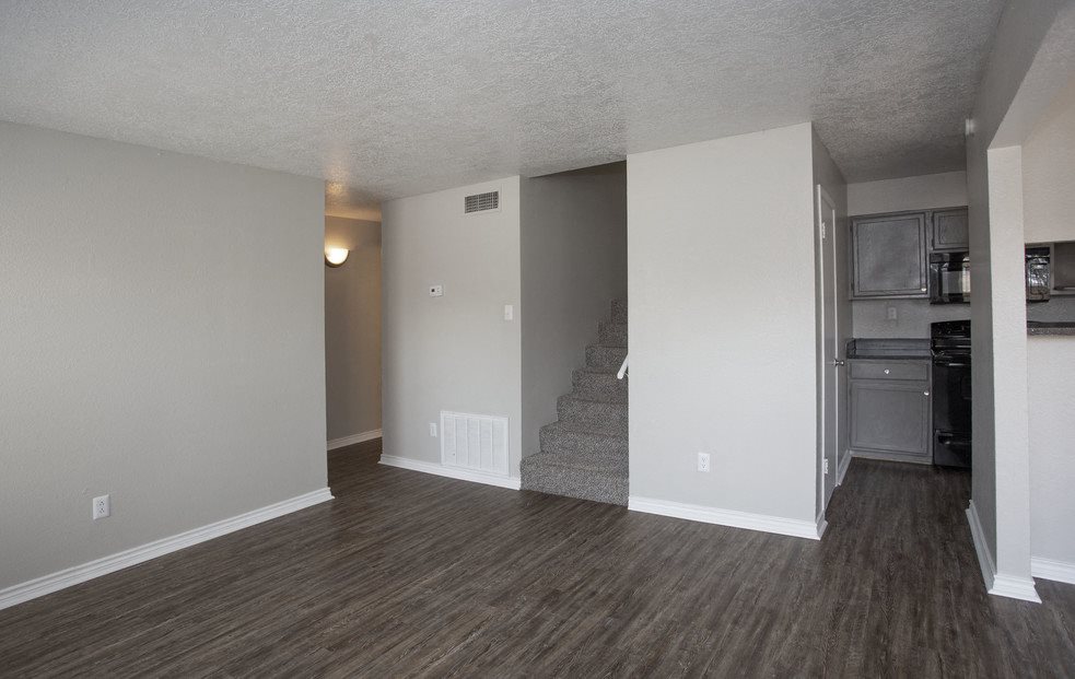 A room with a staircase leading to a kitchen area.